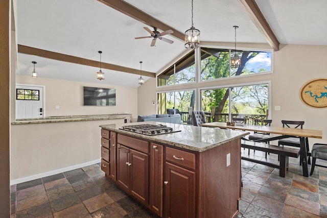 kitchen featuring baseboards, stainless steel gas cooktop, stone tile flooring, and beamed ceiling