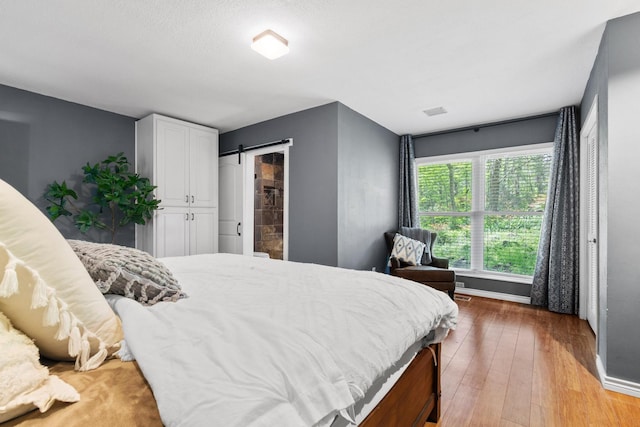 bedroom featuring baseboards, a barn door, and light wood-style floors