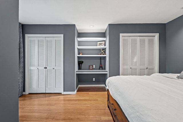 bedroom featuring light wood finished floors, two closets, and baseboards