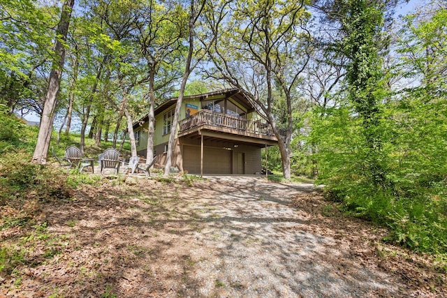 back of property featuring a deck, an attached garage, and driveway