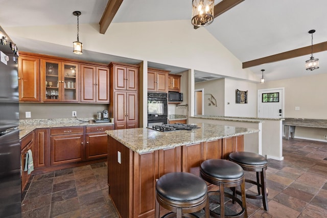 kitchen with beamed ceiling, black appliances, stone tile floors, and brown cabinetry