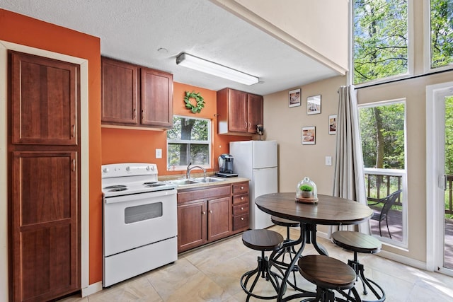 kitchen featuring white appliances, light countertops, a sink, a textured ceiling, and light tile patterned flooring