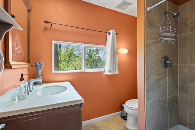 full bathroom with toilet, a tile shower, visible vents, and vanity