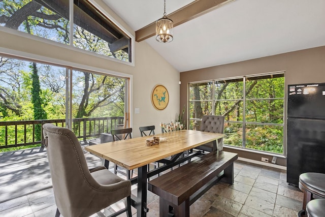 dining room featuring beamed ceiling, a notable chandelier, high vaulted ceiling, and stone tile flooring
