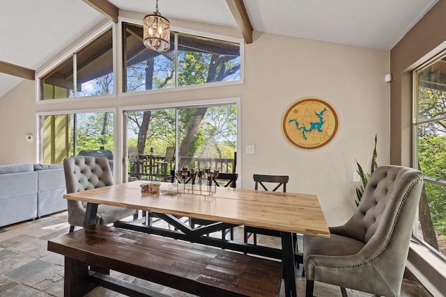 dining space featuring an inviting chandelier, stone finish flooring, a healthy amount of sunlight, and vaulted ceiling with beams