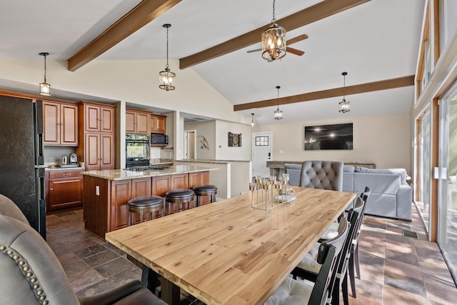 dining space with stone finish floor, lofted ceiling with beams, and a ceiling fan