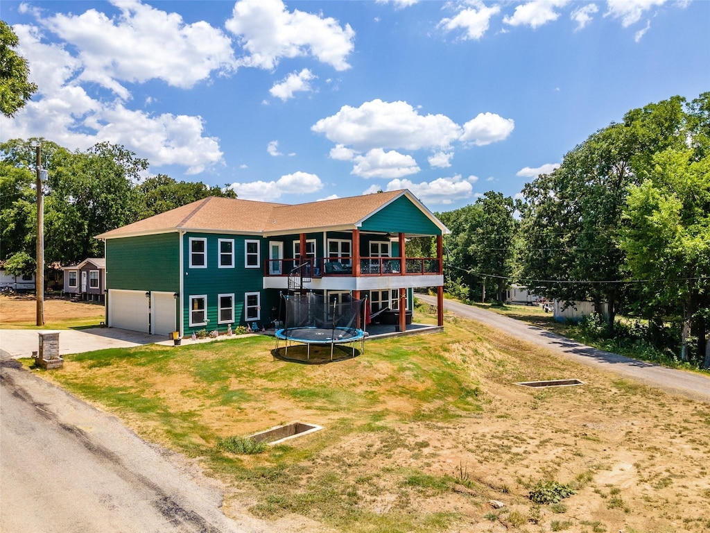 back of house with a lawn, dirt driveway, a deck, and an attached garage