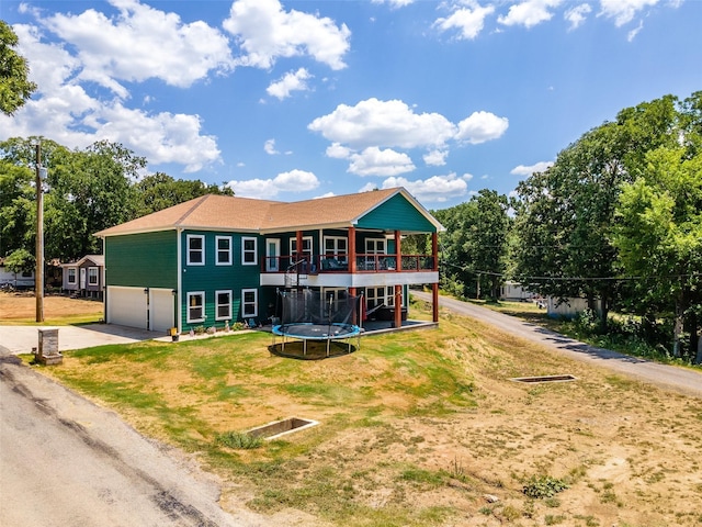 back of house with a lawn, dirt driveway, a deck, and an attached garage