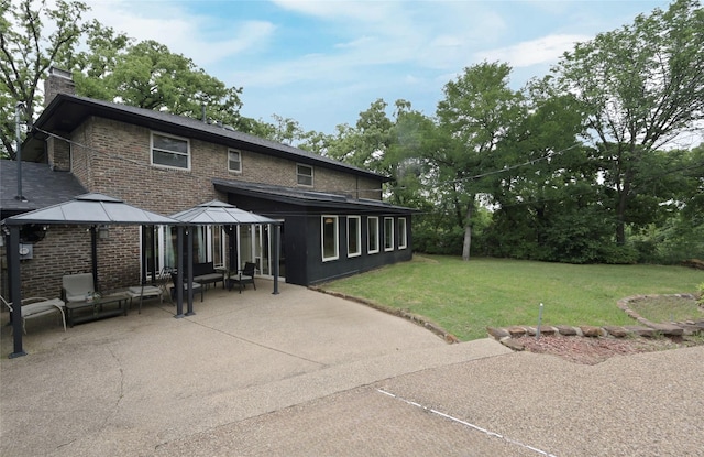 back of house with a chimney, a yard, brick siding, a gazebo, and a patio area