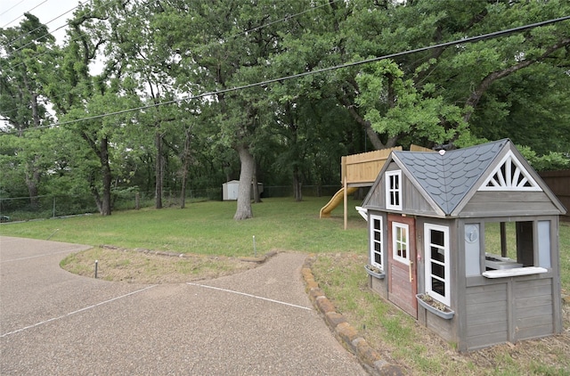 view of yard featuring a fenced backyard, a storage shed, a playground, and an outbuilding
