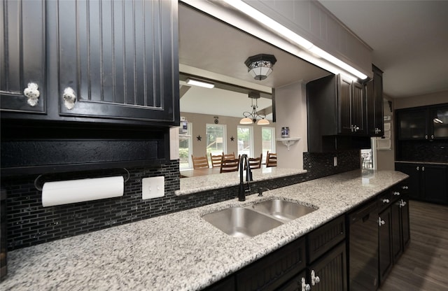 kitchen with dark wood-style floors, light stone countertops, a sink, decorative backsplash, and dishwasher