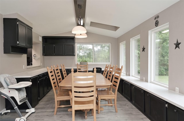 dining room featuring lofted ceiling with beams, a healthy amount of sunlight, and light wood-style flooring
