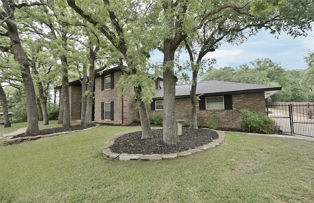view of front facade featuring fence, a front yard, and brick siding