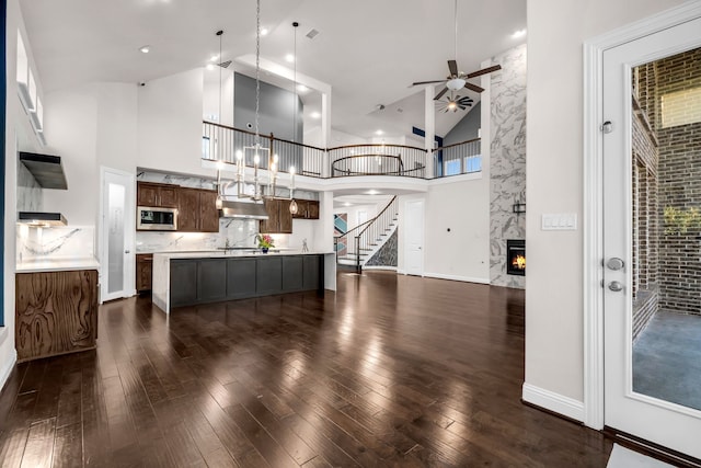509 Basilica Ln, Mckinney, TX 75071 - kitchen featuring stainless steel microwave, a high end fireplace, high vaulted ceiling, open floor plan, and dark wood-style floors