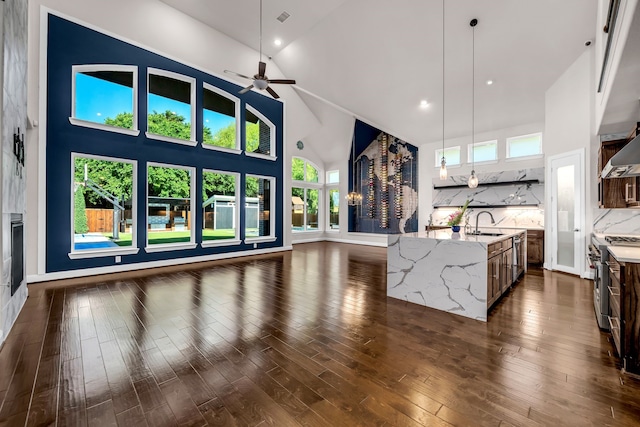 509 Basilica Ln, Mckinney, TX 75071 - kitchen featuring stainless steel range, open floor plan, a sink, high vaulted ceiling, and decorative backsplash