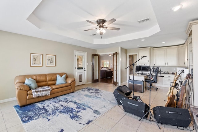 living area with light tile patterned flooring, a raised ceiling, ceiling fan, and visible vents