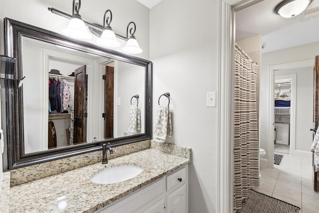 full bath with toilet, tile patterned flooring, vanity, and a spacious closet
