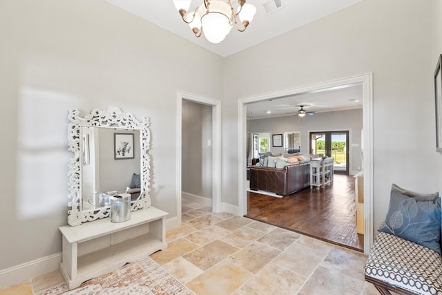 foyer with an inviting chandelier, visible vents, stone finish floor, and baseboards