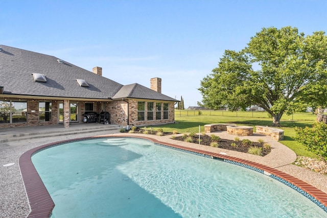 outdoor pool with a lawn, fence, a fire pit, and a patio area