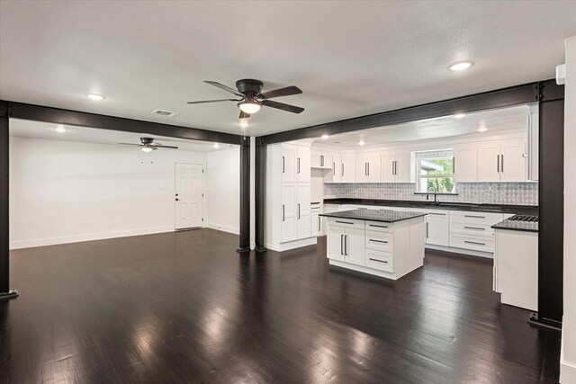 kitchen featuring a sink, dark countertops, white cabinets, a ceiling fan, and backsplash