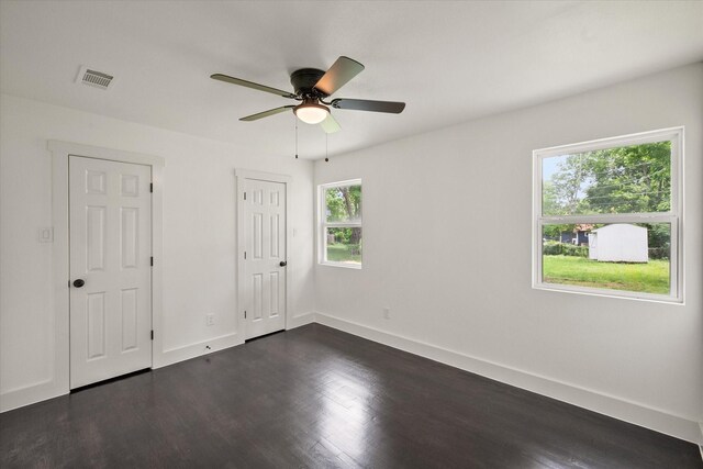 spare room featuring baseboards, a ceiling fan, dark wood-type flooring, and visible vents