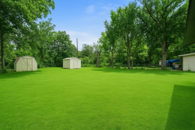 view of yard with an outdoor structure, a shed, and fence