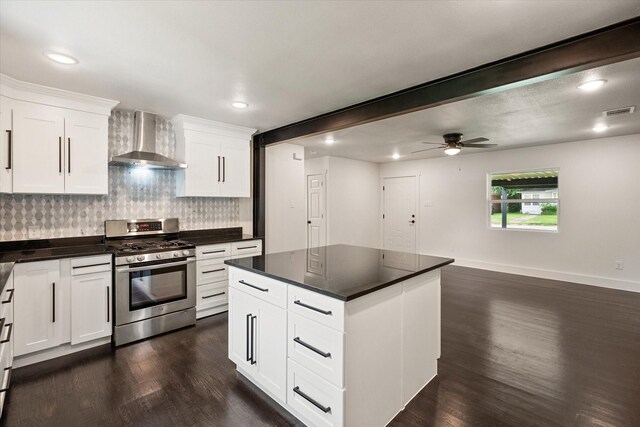 kitchen with visible vents, dark wood-style flooring, dark countertops, stainless steel gas range, and wall chimney exhaust hood