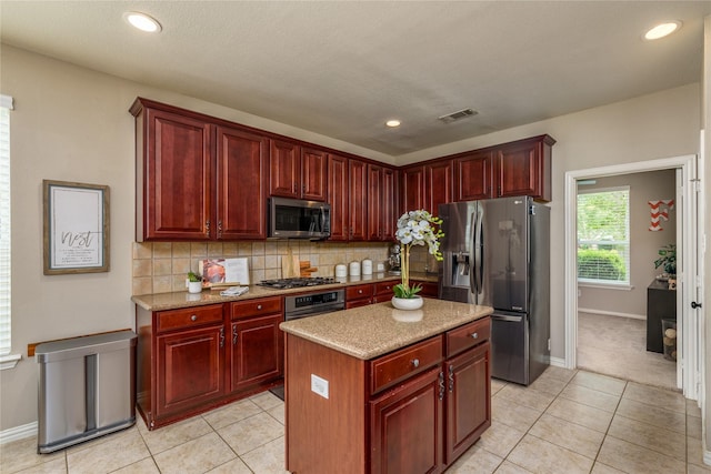 kitchen with appliances with stainless steel finishes, light tile patterned floors, tasteful backsplash, visible vents, and dark brown cabinets
