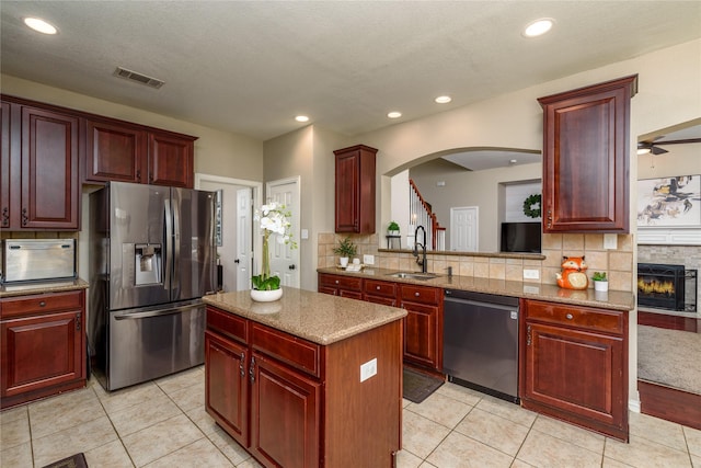 kitchen with a sink, visible vents, stainless steel appliances, dark brown cabinets, and arched walkways