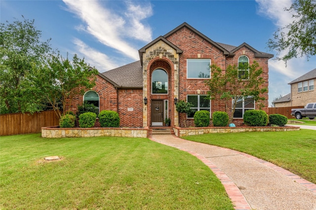 traditional-style home featuring brick siding, fence, and a front yard