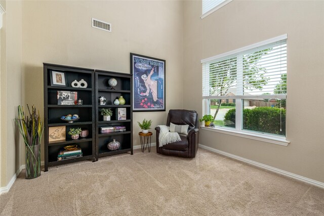 living area featuring a towering ceiling, visible vents, carpet floors, and baseboards