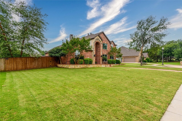 traditional-style house with fence, a front yard, brick siding, and a garage