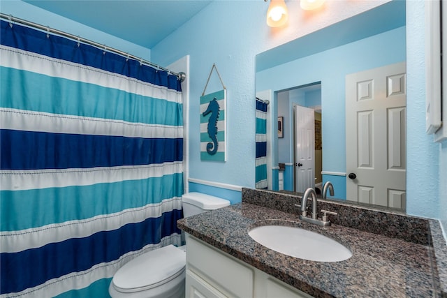 full bathroom featuring toilet, a shower with curtain, a textured wall, and vanity