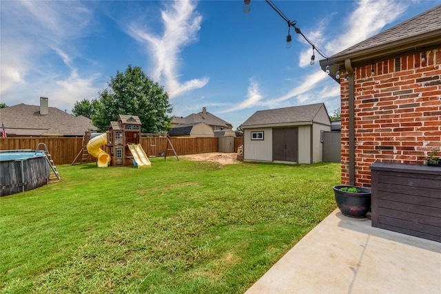 view of yard featuring a fenced in pool, a storage unit, a playground, and a fenced backyard