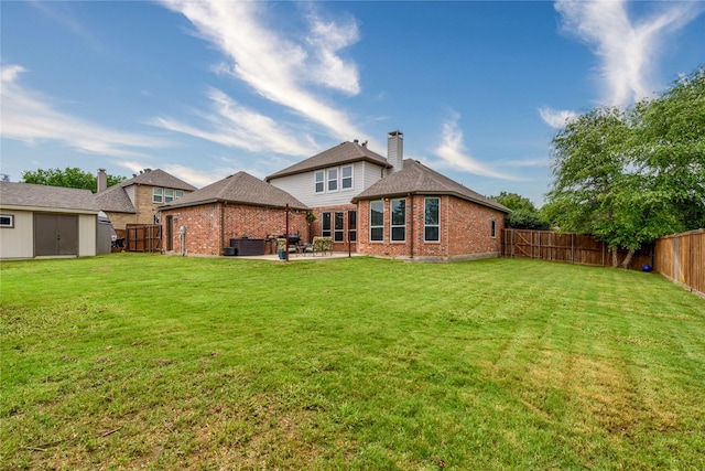 back of house featuring a patio, brick siding, a fenced backyard, and a yard
