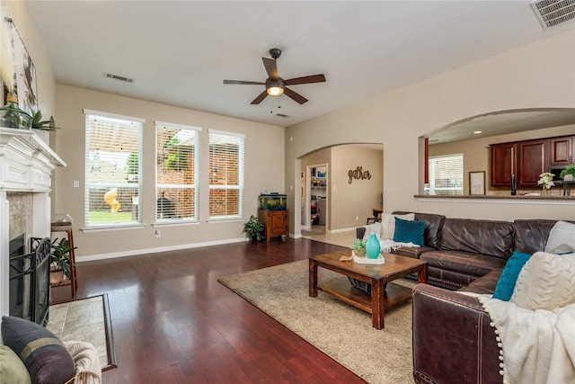 living area featuring arched walkways, ceiling fan, wood finished floors, and visible vents