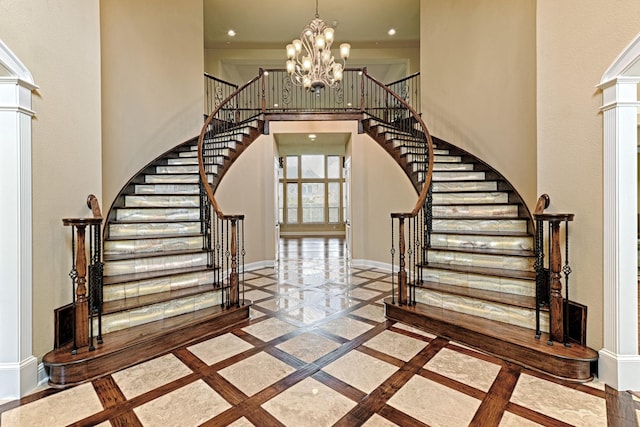stairs featuring recessed lighting, a high ceiling, a chandelier, baseboards, and ornate columns
