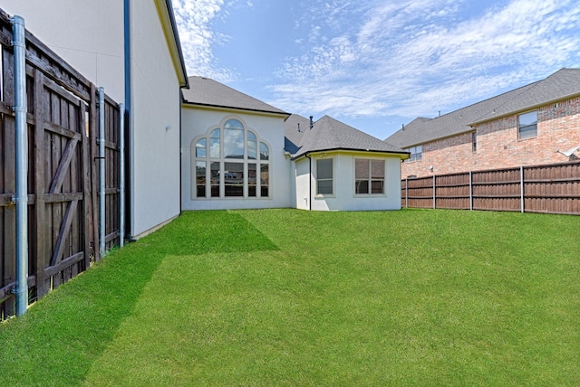 back of property with a fenced backyard, stucco siding, and a lawn