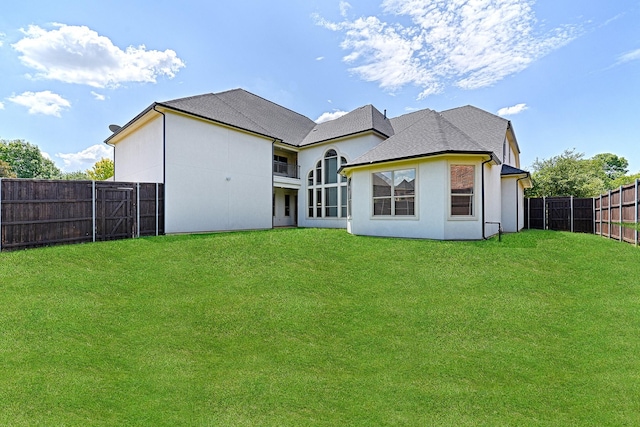 rear view of property featuring a fenced backyard, stucco siding, and a lawn