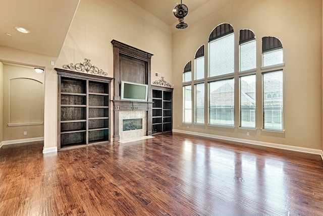 unfurnished living room with wood finished floors, a high end fireplace, and baseboards