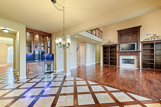 interior space featuring beverage cooler, visible vents, baseboards, an inviting chandelier, and a fireplace