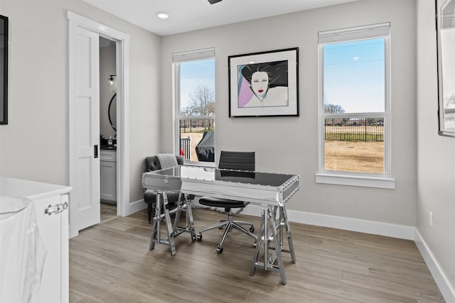 office featuring baseboards, a ceiling fan, and light wood-style flooring