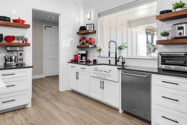 kitchen with a sink, open shelves, a toaster, stainless steel dishwasher, and dark countertops