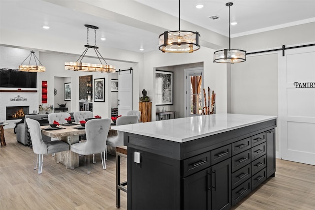 kitchen with visible vents, light wood-style flooring, a barn door, and light countertops