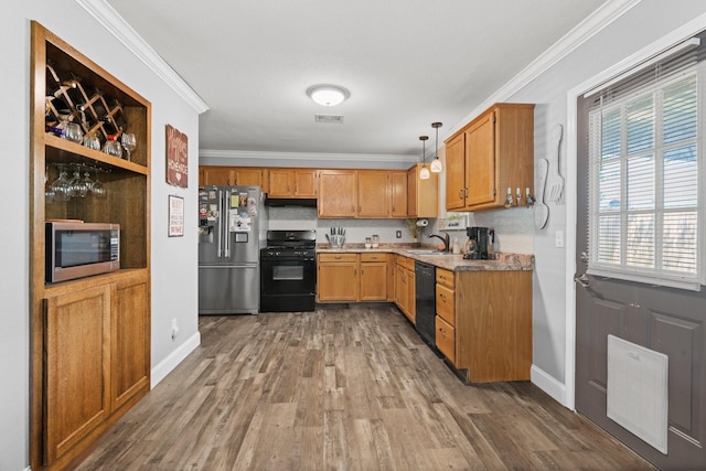 kitchen featuring wood finished floors, black appliances, ornamental molding, a sink, and visible vents