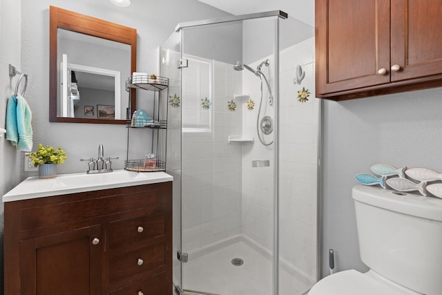 full bath featuring toilet, vanity, and a shower stall