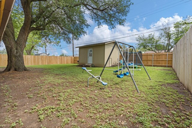 view of yard with a trampoline, a fenced backyard, a playground, and an outdoor structure
