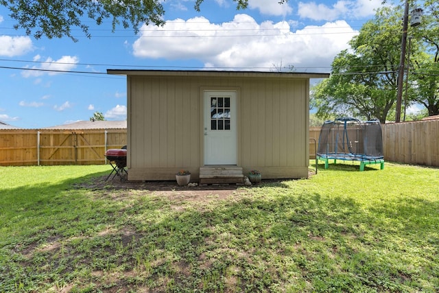 view of outdoor structure featuring a fenced backyard, an outbuilding, entry steps, and a trampoline