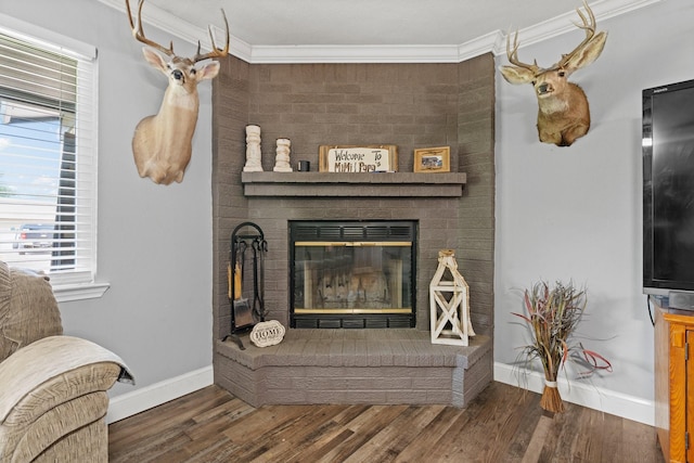 living room with ornamental molding, a healthy amount of sunlight, wood finished floors, and a brick fireplace