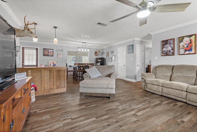 living room with visible vents, wood finished floors, ceiling fan with notable chandelier, and crown molding